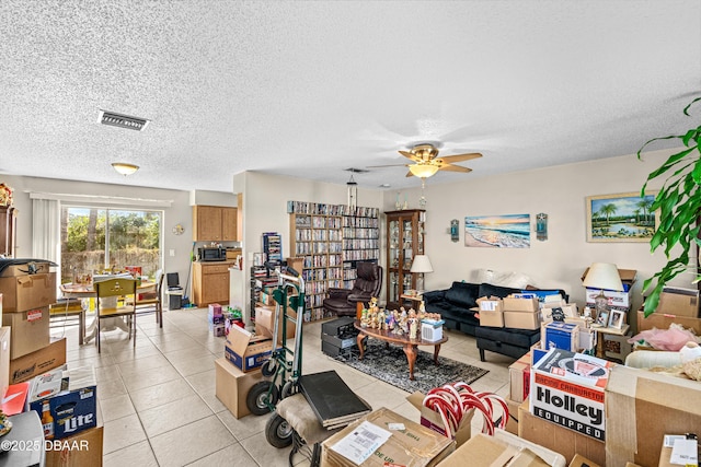 living room with ceiling fan, visible vents, a textured ceiling, and light tile patterned flooring