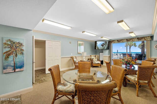 carpeted dining room with ornamental molding