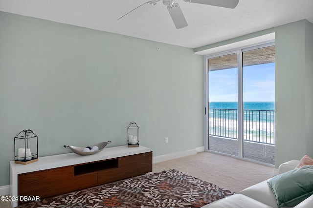 carpeted home office with a textured ceiling, a water view, and ceiling fan