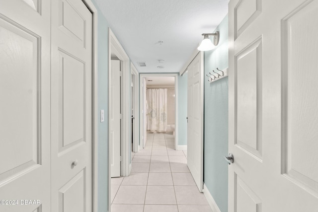 hallway featuring light tile patterned floors and a textured ceiling