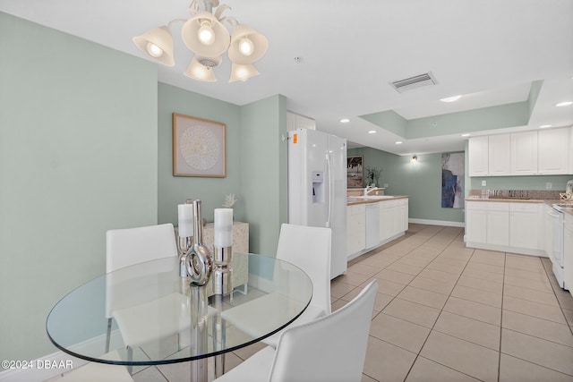 dining area featuring light tile patterned floors, a raised ceiling, and a notable chandelier