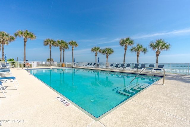 view of swimming pool featuring a water view and a patio