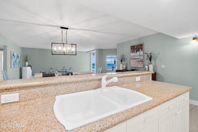 kitchen with white cabinetry, sink, a notable chandelier, pendant lighting, and light tile patterned floors