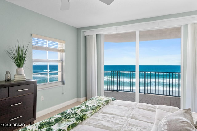 carpeted bedroom with access to exterior, ceiling fan, and a water view