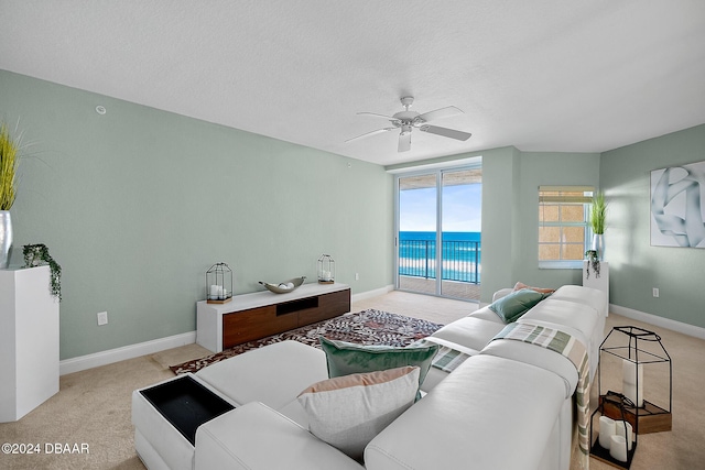 carpeted living room with ceiling fan, a water view, and a textured ceiling