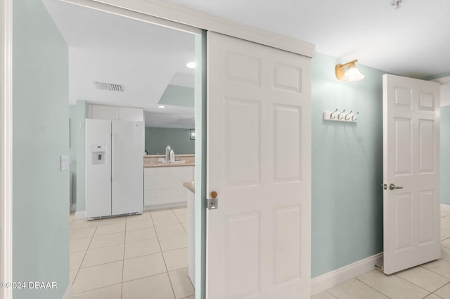 hall featuring sink and light tile patterned flooring