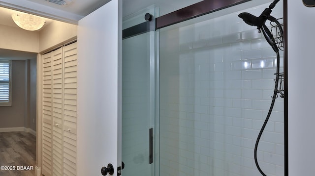 bathroom with a shower with door and hardwood / wood-style floors