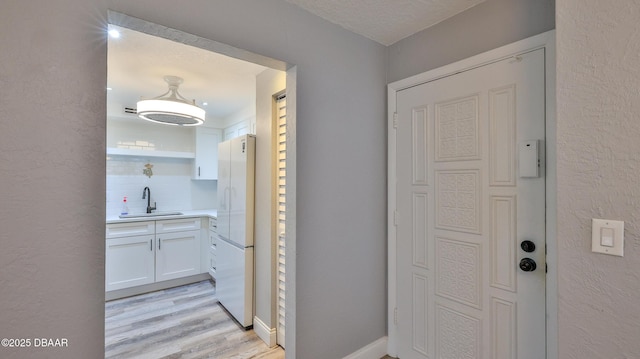 corridor featuring sink, a textured ceiling, and light hardwood / wood-style flooring