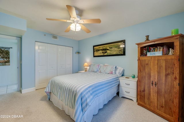 bedroom featuring light carpet, ceiling fan, and a closet