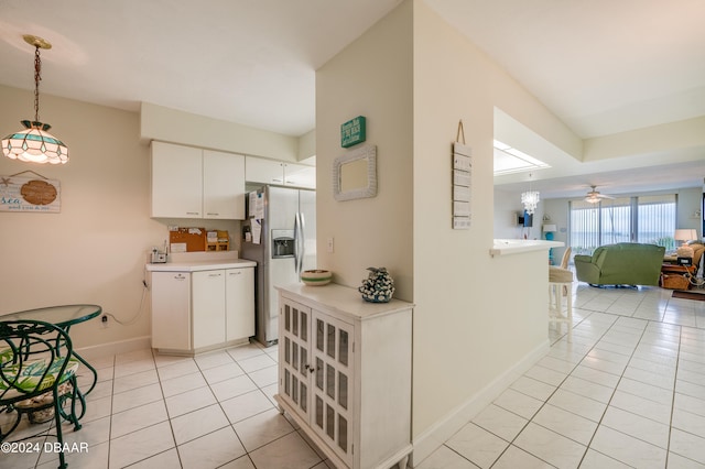 kitchen featuring white cabinetry, hanging light fixtures, light tile patterned flooring, and stainless steel fridge with ice dispenser