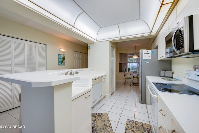 kitchen with white cabinets, sink, light tile patterned flooring, a breakfast bar, and white appliances