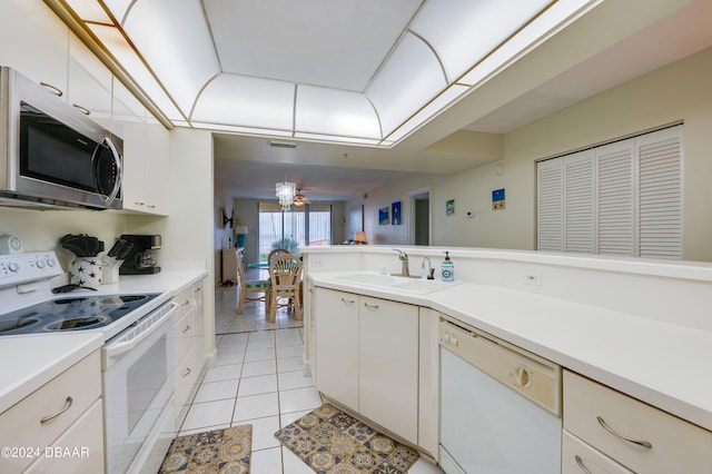 kitchen featuring white appliances, sink, light tile patterned flooring, and white cabinets