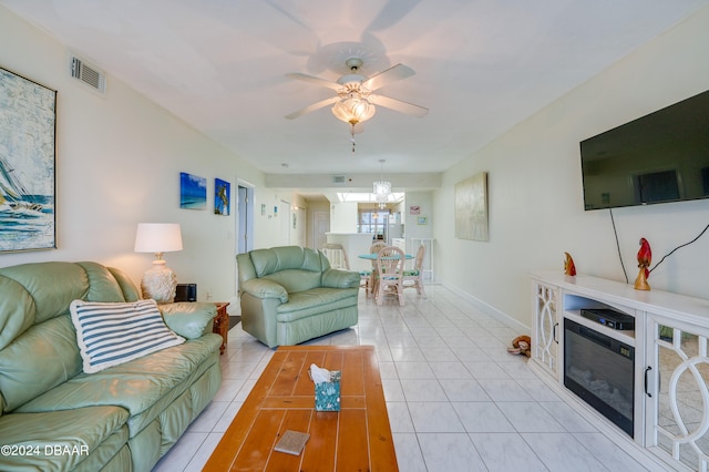 tiled living room with ceiling fan with notable chandelier