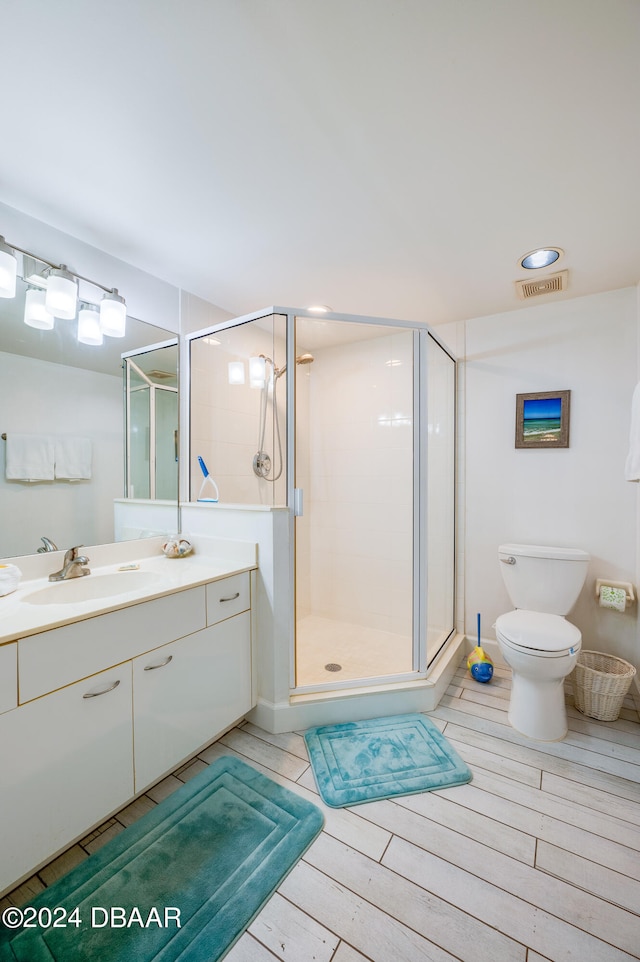 bathroom with hardwood / wood-style flooring, vanity, toilet, and an enclosed shower