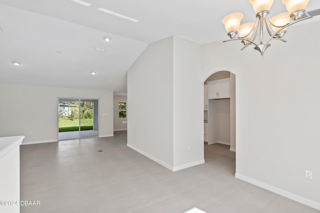 unfurnished room with lofted ceiling, light tile patterned floors, and a notable chandelier