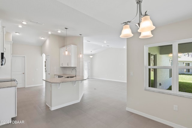 kitchen featuring white cabinets, hanging light fixtures, sink, and lofted ceiling