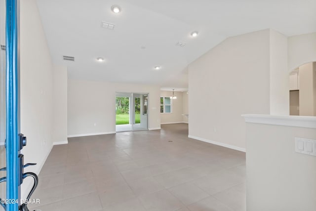 unfurnished room with lofted ceiling and light tile patterned flooring