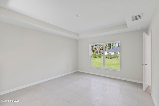 tiled spare room featuring a raised ceiling