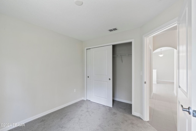 unfurnished bedroom featuring light carpet and a closet