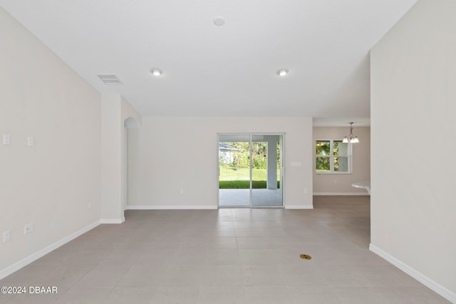 unfurnished room with a notable chandelier and light tile patterned floors