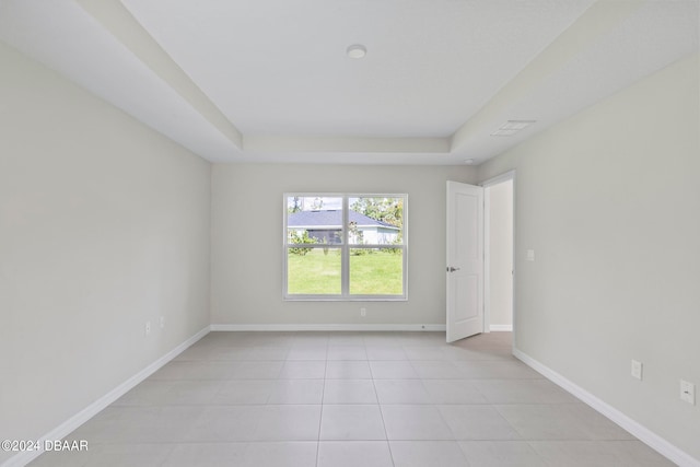 empty room featuring light tile patterned floors and a raised ceiling