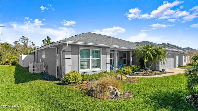 back of property featuring a shingled roof, concrete driveway, stucco siding, a yard, and an attached garage