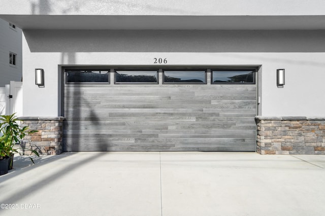 exterior space featuring driveway, stucco siding, and stone siding
