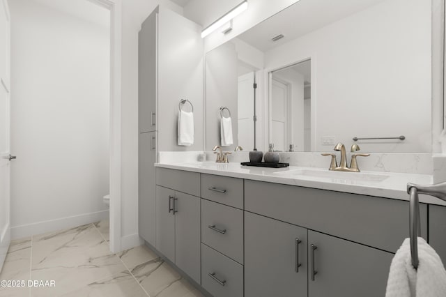 bathroom featuring visible vents, marble finish floor, a sink, double vanity, and baseboards