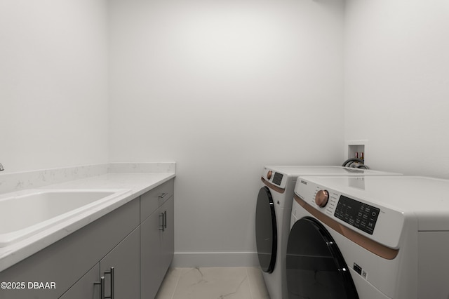 laundry area with baseboards, a sink, cabinet space, washing machine and clothes dryer, and marble finish floor