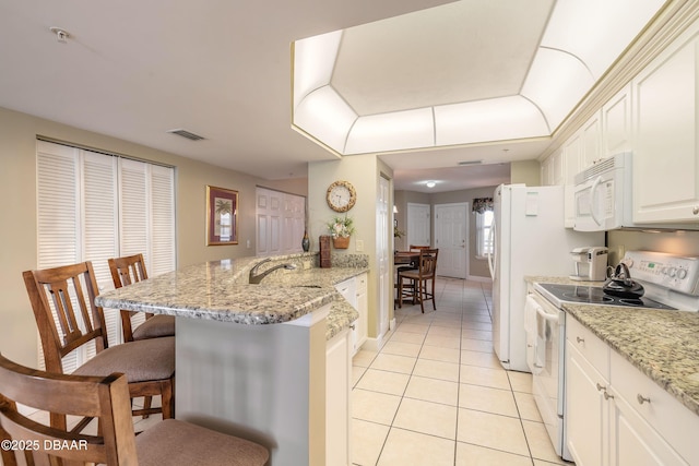 2055 S Atlantic Ave Unit 710, Daytona Beach, FL 32118 - kitchen with white appliances, a breakfast bar, light tile patterned flooring, a peninsula, and a sink