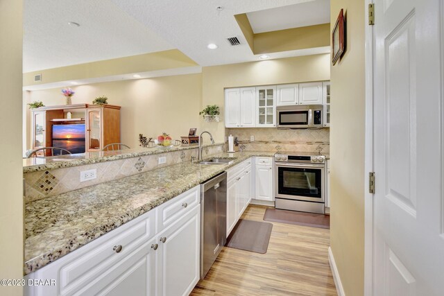 4670 Links Village Dr Unit B102, Ponce Inlet, FL 32127 - kitchen featuring stainless steel appliances, a sink, light wood-style flooring, white cabinetry, and recessed lighting
