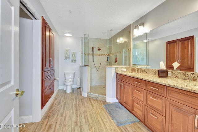 4670 Links Village Dr Unit B102, Ponce Inlet, FL 32127 - bathroom with vanity, a tile shower, wood finished floors, toilet, and a textured ceiling
