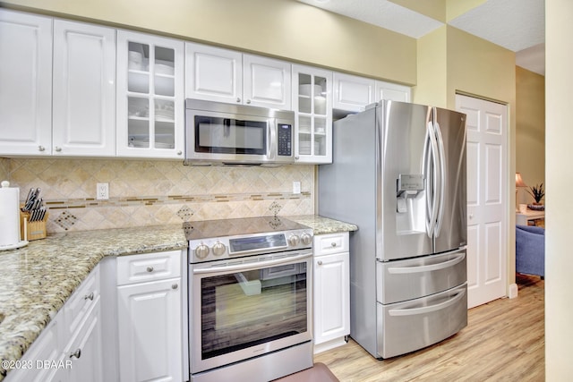 4670 Links Village Dr Unit B102, Ponce Inlet, FL 32127 - kitchen with stainless steel appliances, light wood-style floors, white cabinetry, and tasteful backsplash