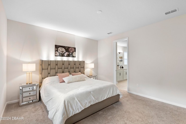 bedroom featuring ensuite bathroom and light colored carpet