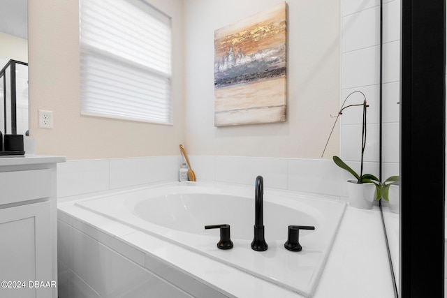 bathroom with vanity and tiled bath