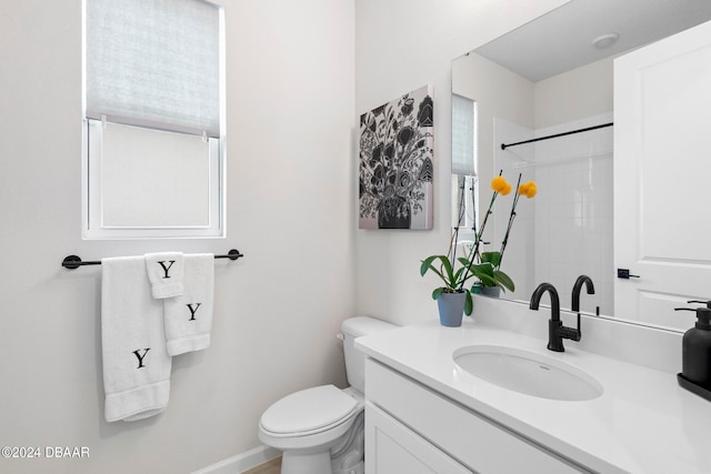 bathroom featuring toilet, vanity, and a tile shower