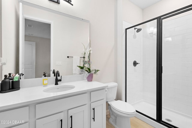 bathroom featuring vanity, hardwood / wood-style flooring, toilet, and a shower with door