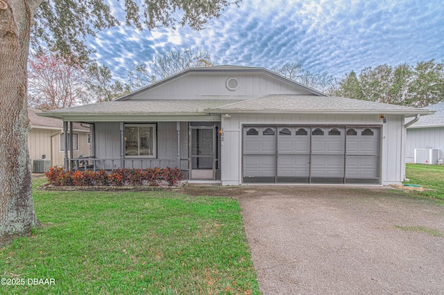 ranch-style home featuring a porch, a garage, central air condition unit, and a front lawn