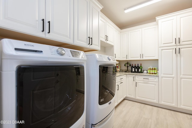 838 Attitude Ave, Daytona Beach, FL 32124 - laundry area featuring separate washer and dryer, cabinet space, and light wood-style floors