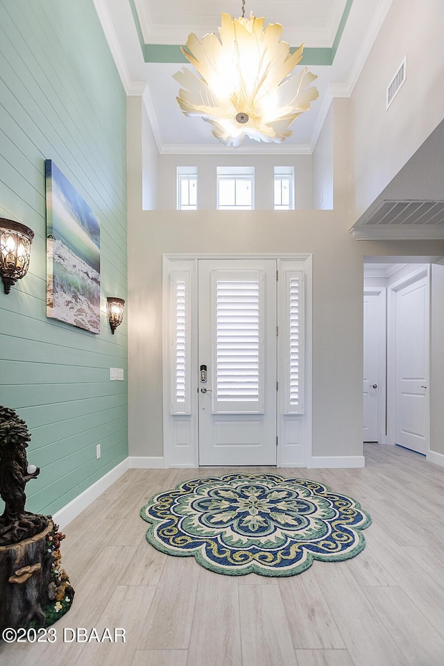 838 Attitude Ave, Daytona Beach, FL 32124 - foyer entrance featuring a chandelier, wood finished floors, a towering ceiling, ornamental molding, and baseboards