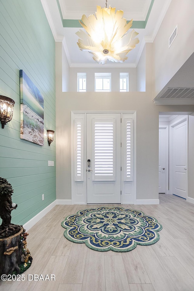 838 Attitude Ave, Daytona Beach, FL 32124 - foyer with a chandelier, wood finished floors, a high ceiling, ornamental molding, and baseboards