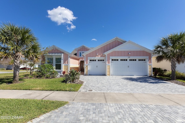 838 Attitude Ave, Daytona Beach, FL 32124 - view of front facade featuring board and batten siding, a garage, decorative driveway, and a front lawn