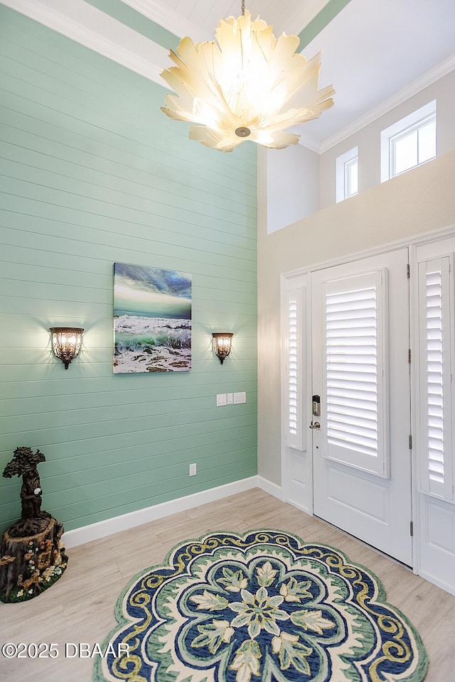 838 Attitude Ave, Daytona Beach, FL 32124 - foyer with a chandelier, crown molding, light wood-style flooring, a high ceiling, and baseboards