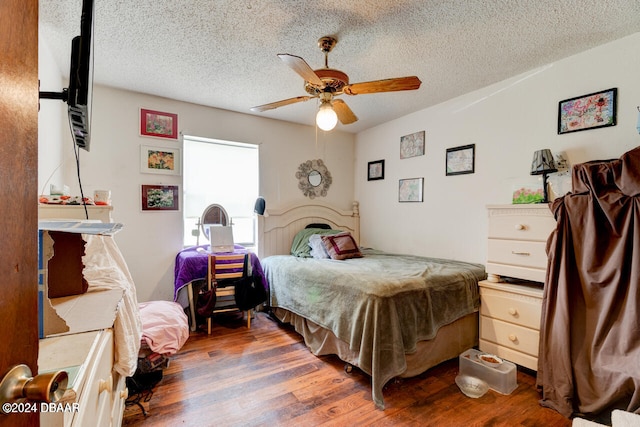 bedroom with ceiling fan, dark wood-type flooring, and a textured ceiling