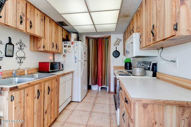 kitchen featuring light tile patterned flooring, white appliances, and sink