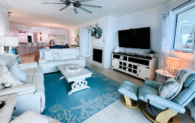 living room with ceiling fan, a tiled fireplace, dark hardwood / wood-style flooring, and ornamental molding