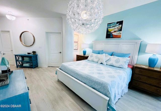 bedroom with light wood-type flooring and a notable chandelier