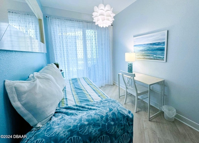 bedroom with hardwood / wood-style floors and a notable chandelier