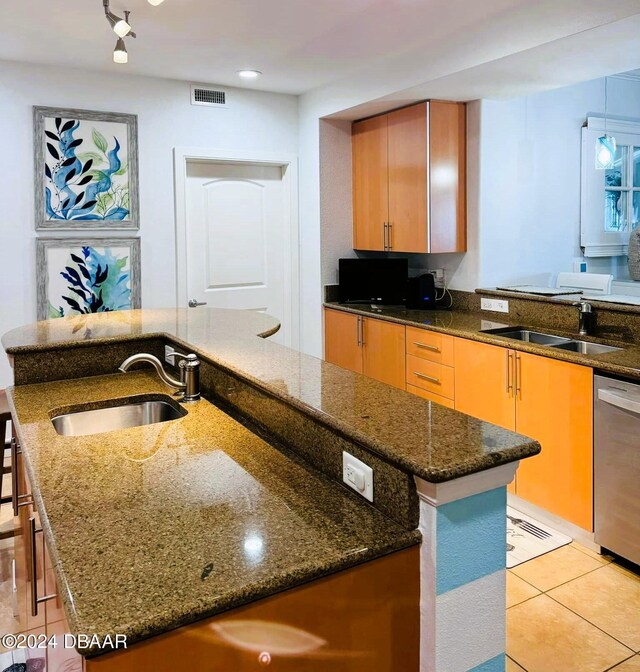 kitchen with stainless steel dishwasher, a center island with sink, sink, and dark stone countertops