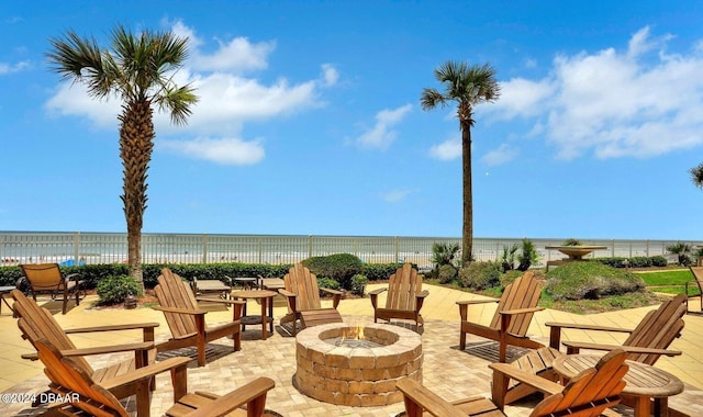 view of patio / terrace with a beach view, a water view, and a fire pit